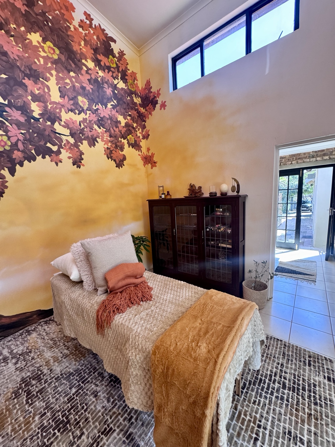 Warm treatment room beneath the autumn-coloured Tree of Life mural